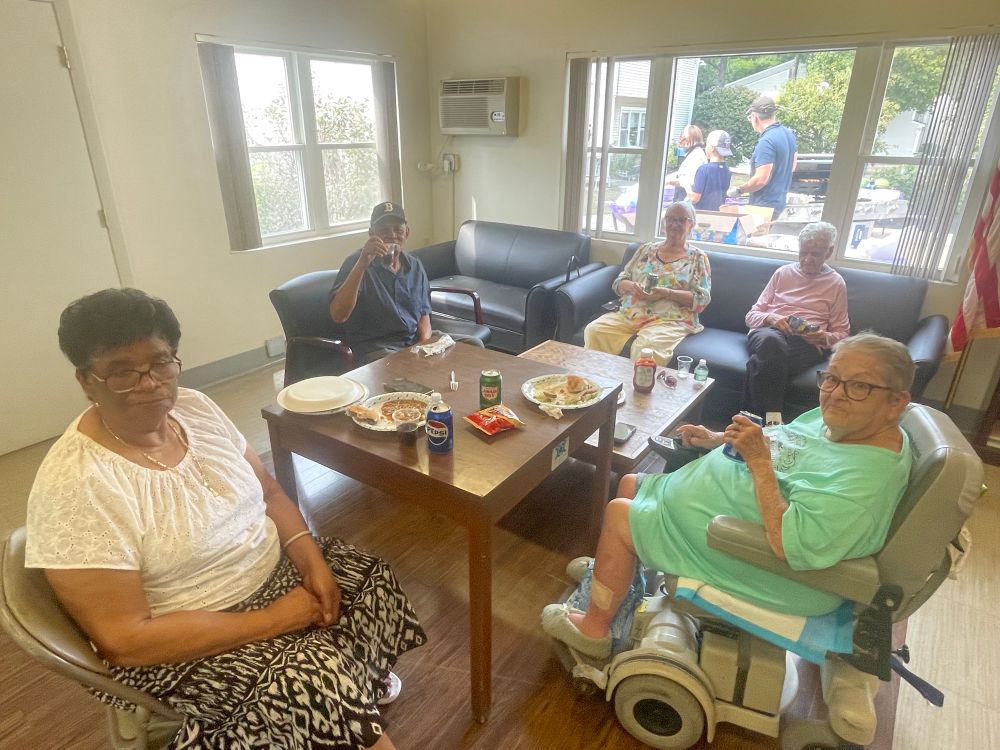 Five BHA residents enjoying their food inside the community room