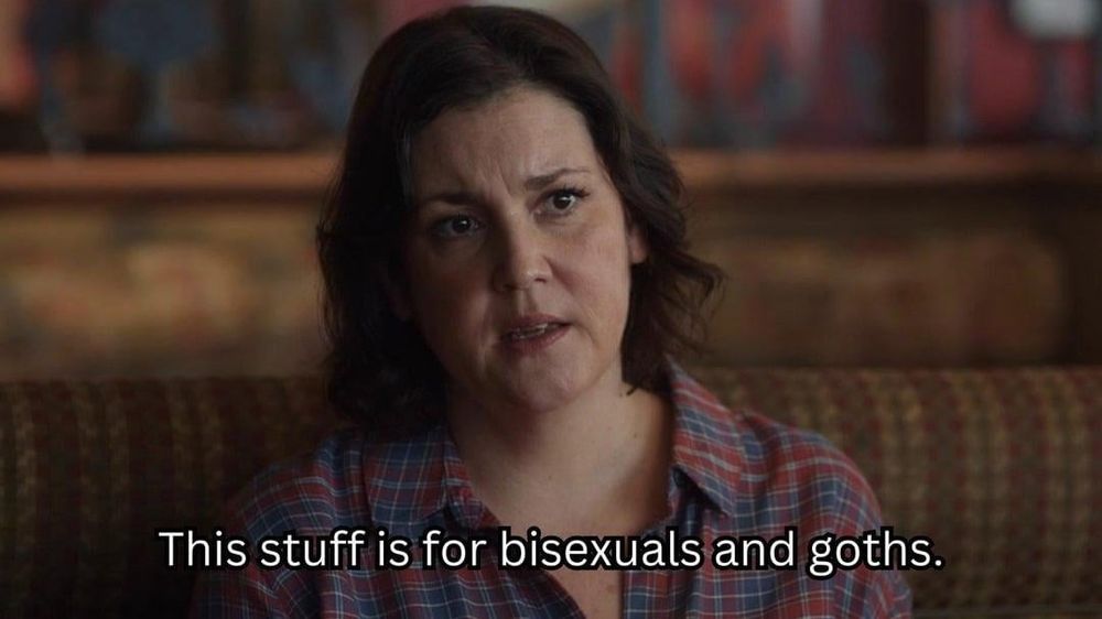 Melanie Lynsky sitting in a restaurant booth with the text "this stuff is for bisexuals and goths." 