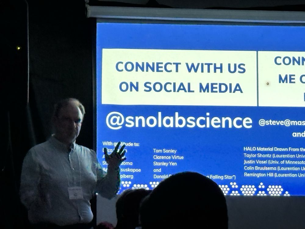 A person talking to an audience in front of a projected slide.