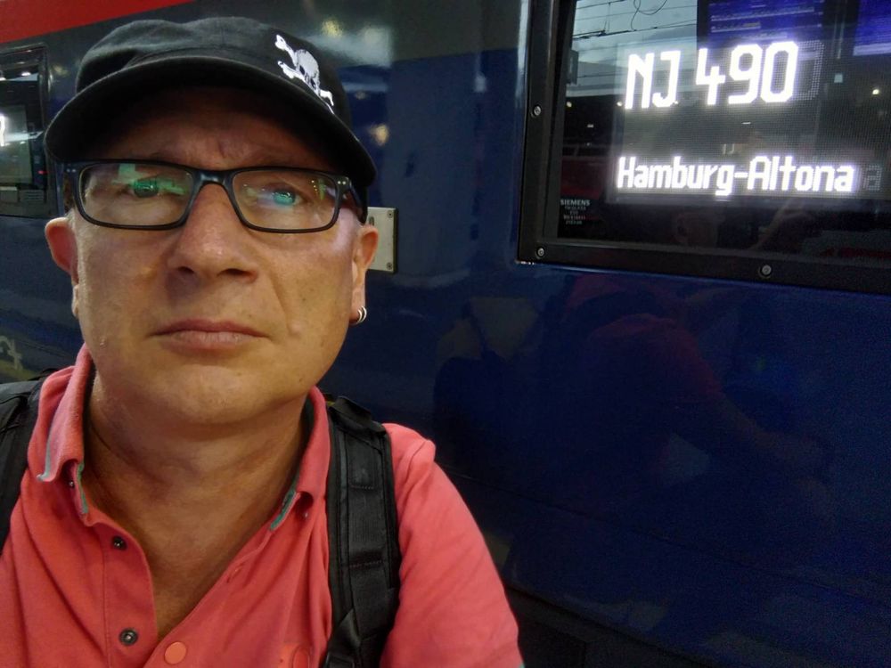 Ich mit Brille und schwarzer St. Pauli Kappe vor einem Zug mit Außenscreen (NJ 490, Hamburg-Altona)