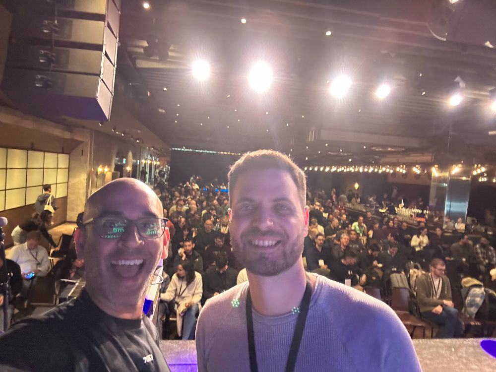 2 people standing on stage in front of a crowd 