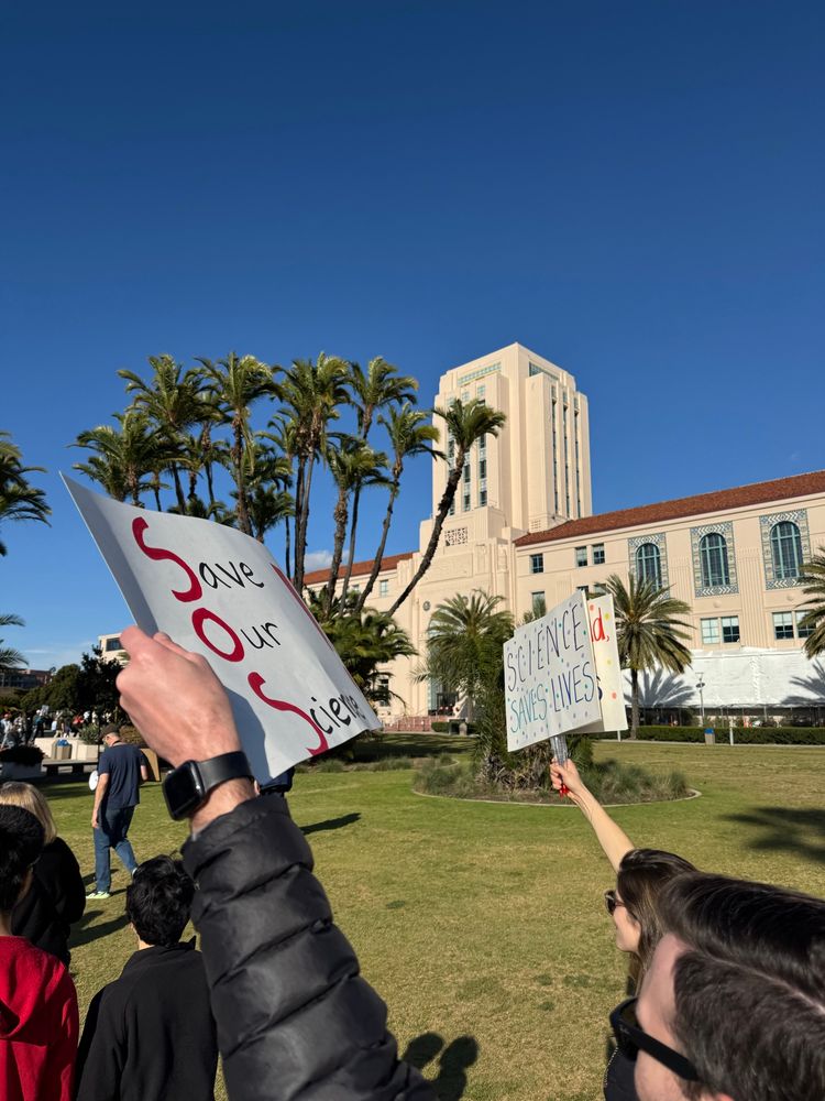 Protest signs in front of the San Diego waterfront building that says ‘Save our science’ and ‘Science saves lives’ 
