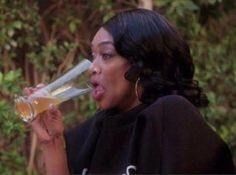 Une personne noire ( que j'identifie comme une femme) habillée en noir, les cheveux attachés.

Elle boit un verre de bière tout en affichant moue moqueuse.