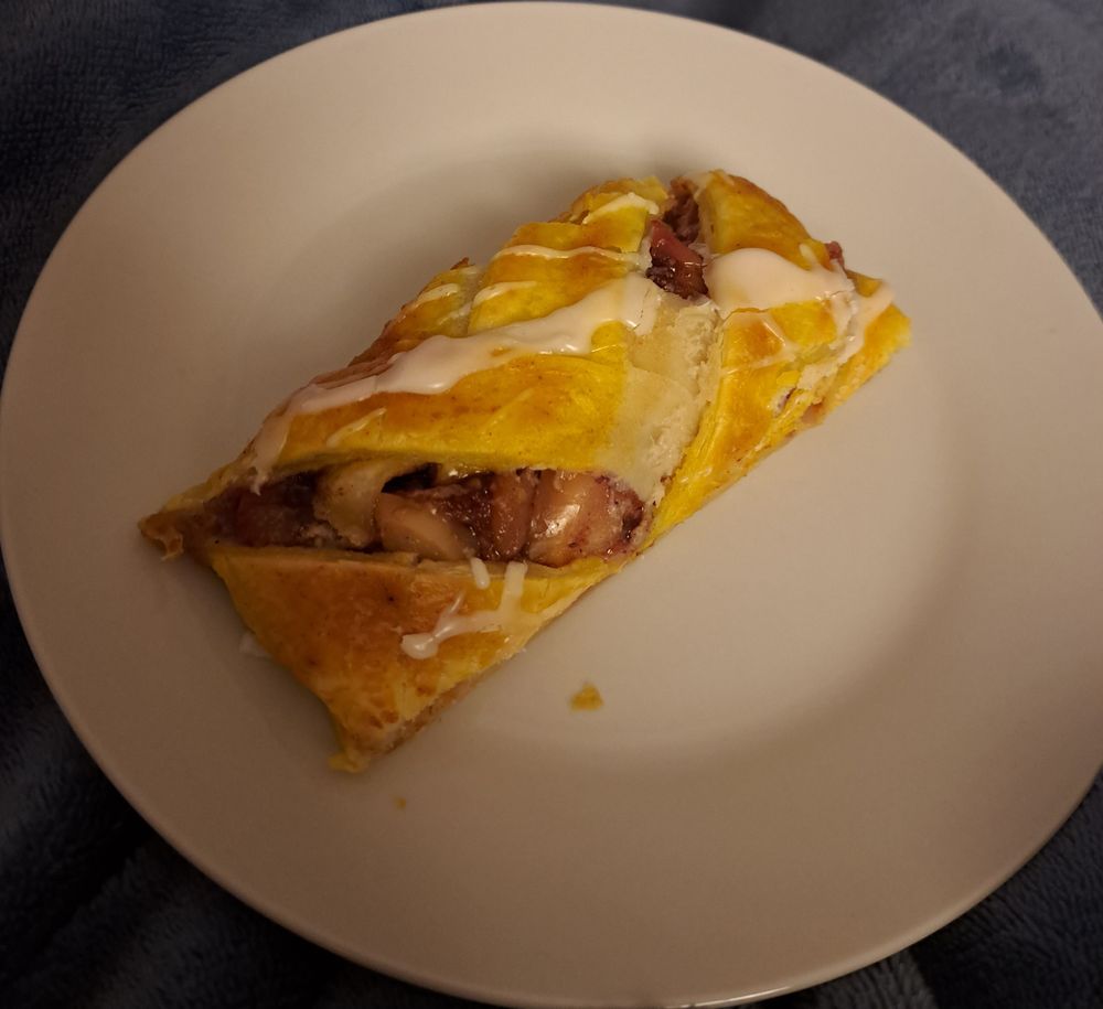 Ein Stück Cheesecake-Apfelstrudel (mit Preiselbeeren) auf einem weißen Teller.