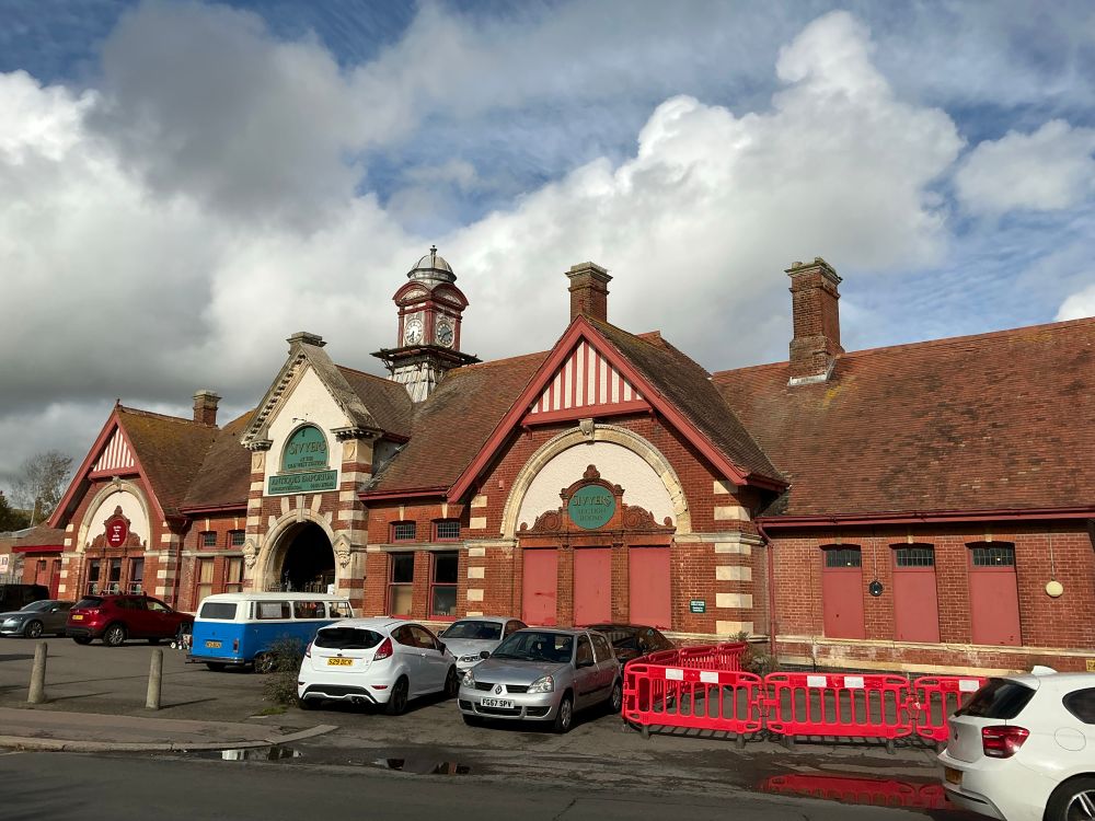 The outside of the large Edwardian building. It has a clock tower above and just behind the entrance. 