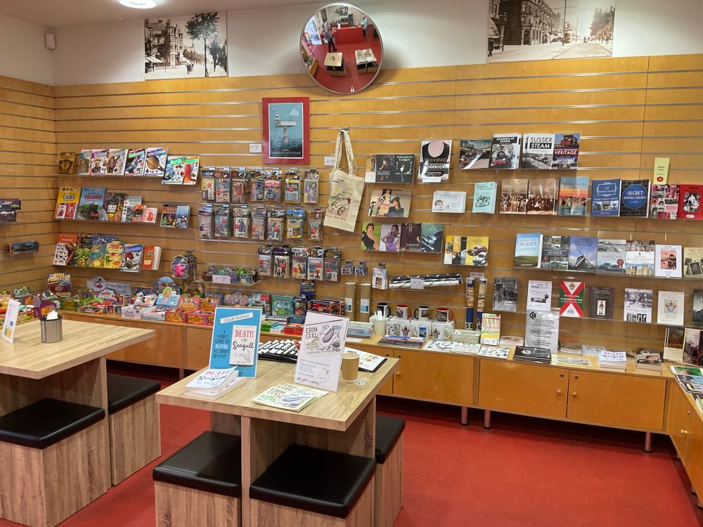 A wide shot of the back wall of the gift shop. There are books both for children and adults, packs of mementos of different historical subjects, posters of the Sovereign Light and much more. 
