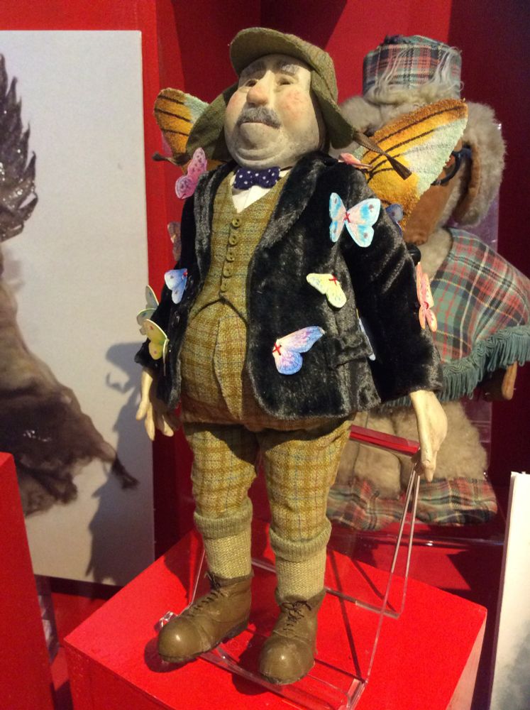 The picture shows a model of a man dressed in tweed trousers and waistcoat and a black velvet jacket. The jacket has butterflies all over it. He also has wings! The face is so expressive and well modelled.  
