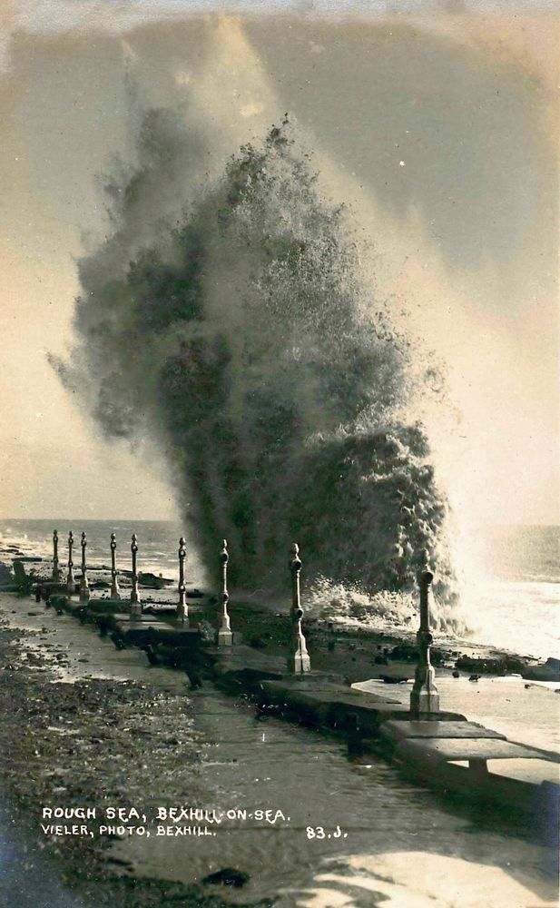 Black and white photograph as postcard. Wave breaking over a damaged sea wall, Bexhill-On-Sea, Sussex c.1913.