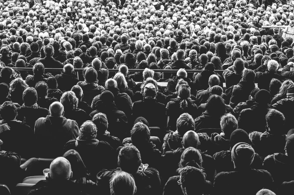Black and white photo of the backs of people's heads in a crowd