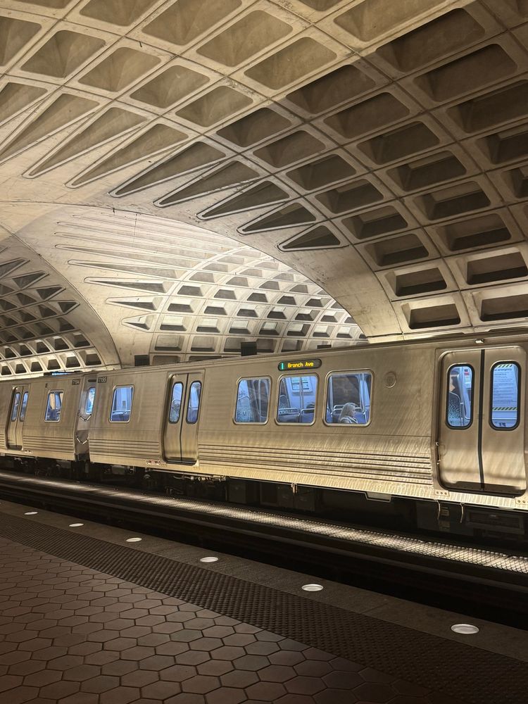 A picture of a DC metro station with a green line train in the foreground 