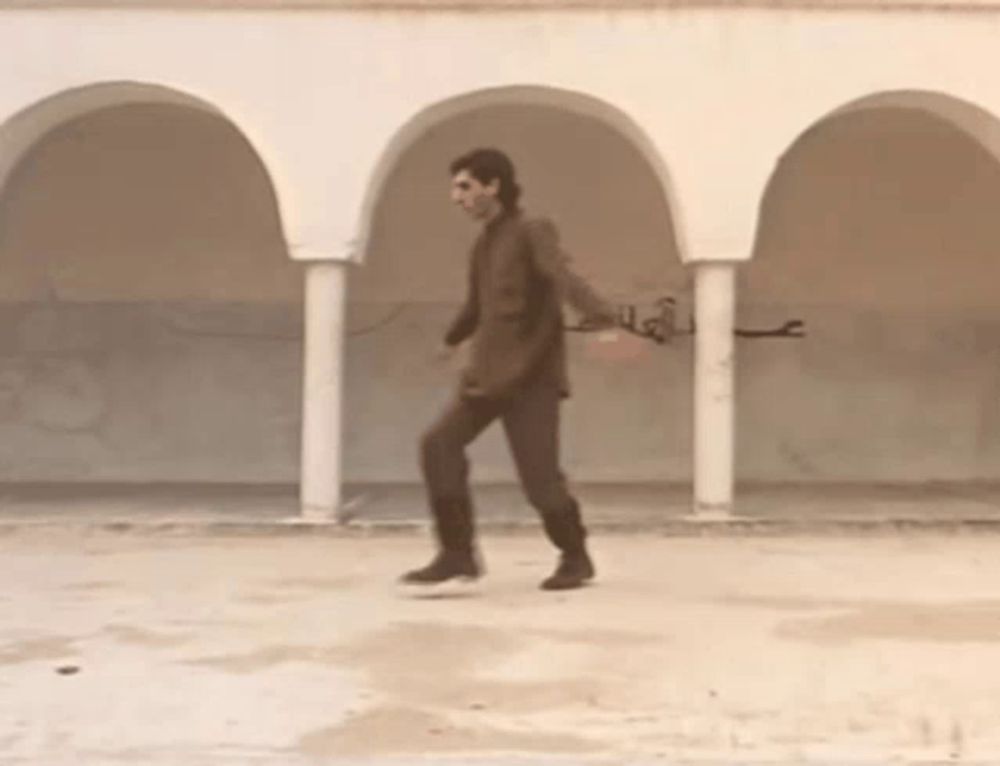 a man in a suit is walking under arches