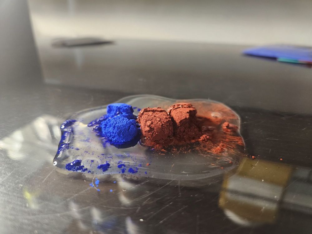 Red and blue pigment in a pool of watercolor binder 