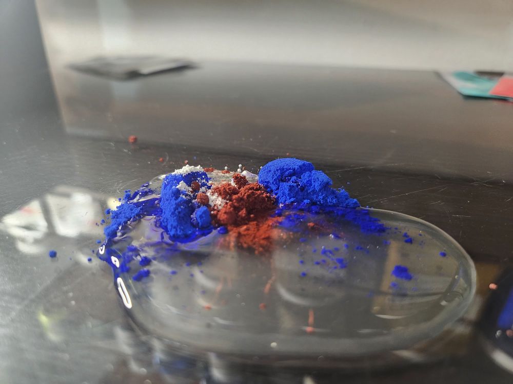 Red, blue and white pigment in a pool of watercolor binder