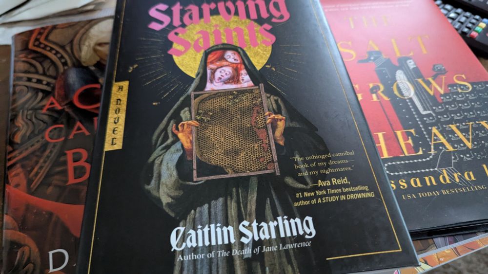 The covers of three books: A Curse Carved in Bone by Danielle L. Jensen, The Starving Saints by Caitlin Starling, The Salt Grows Heavy by Cassandra Khaw.