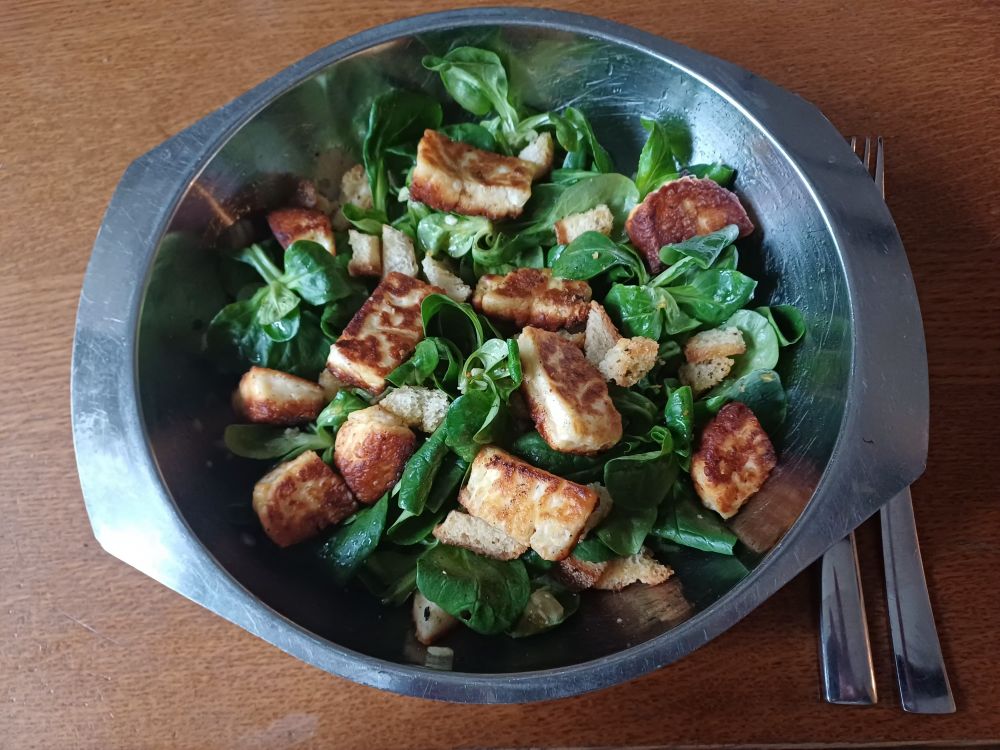 Schüssel Feldsalat getoppt mit Croutons und Halloumi.