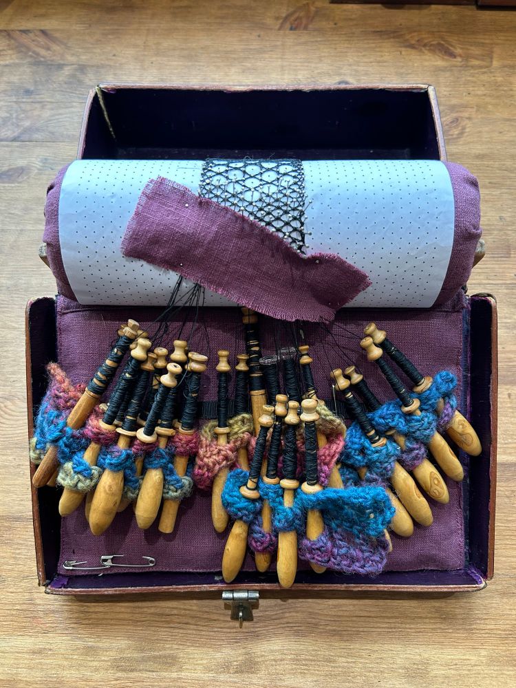 The travel pillow with all of the bobbins enlaced by colorful blue, purple, and magenta strips.