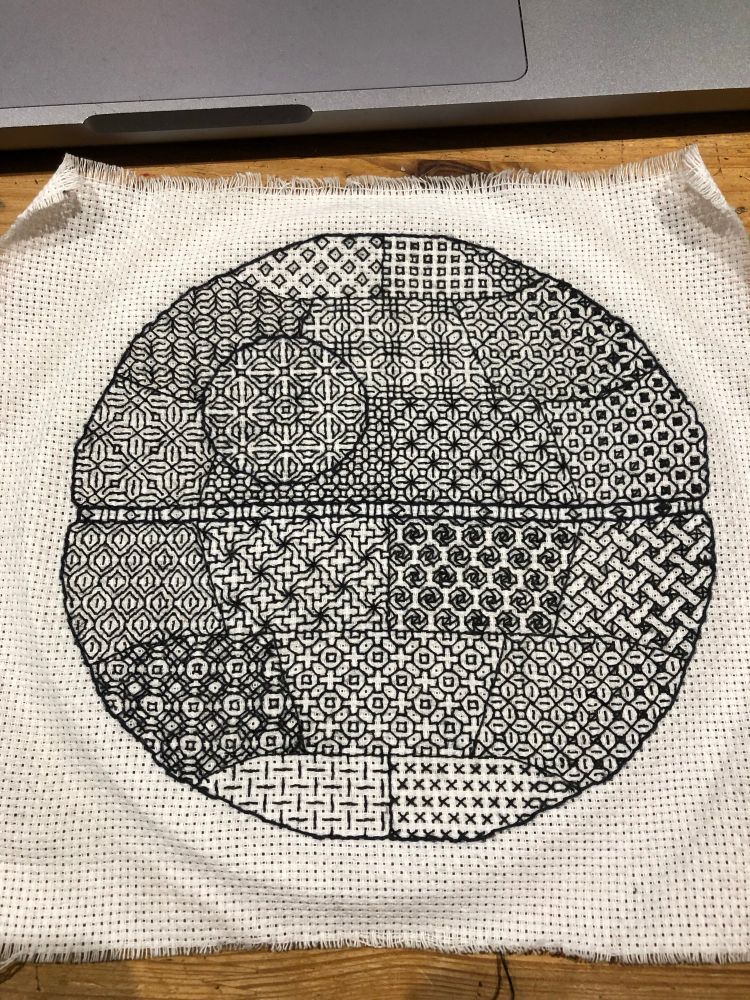 An embroidered Death Star with different patterns in black thread in each of the segments.