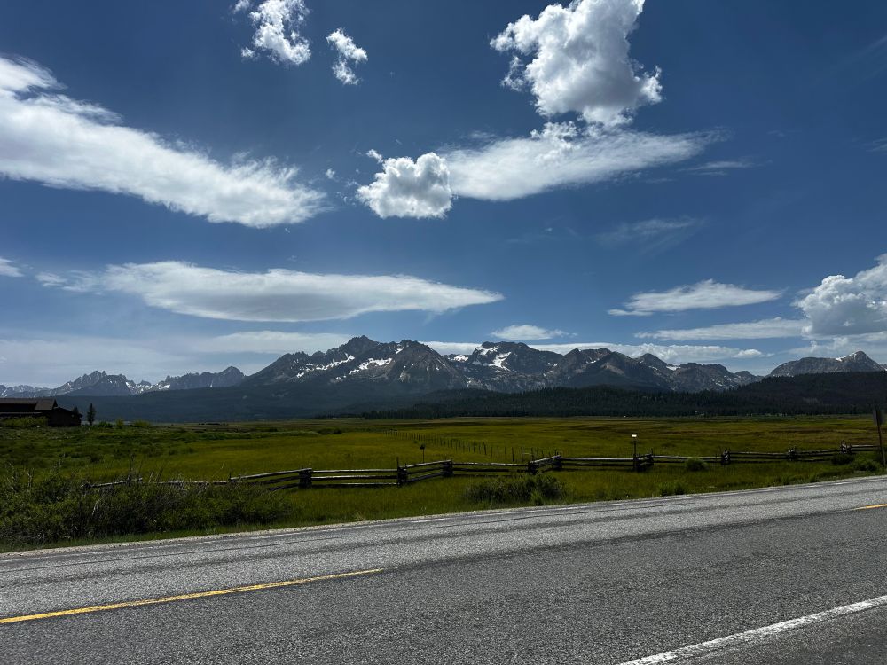 Scenic shot of sub-alpine terrain with a snowy mountain in the background. Clouds are wispy 