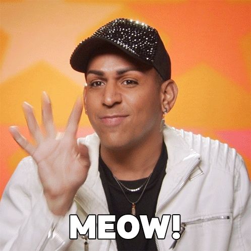 a man wearing a hat and a white jacket says meow with his hand