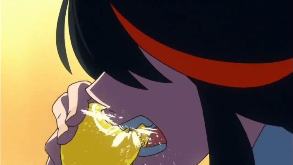 Ryuko Matoi in her first scene in Kill La Kill eating a lemon. A girl with dark hair with a red streak that obscures her eyes, seen in close-up biting into a lemon still in its peel.