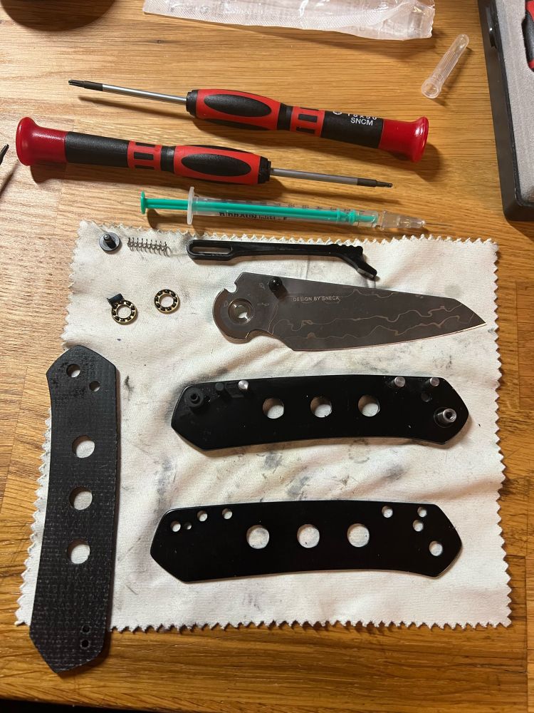 Vollständig zerlegtes Taschenmesser auf einem Mikrofasertuch. Die einzelnen Teile sind sauber angeordnet.