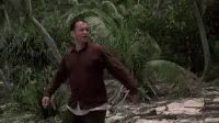 a man in a red shirt is walking through a forest .