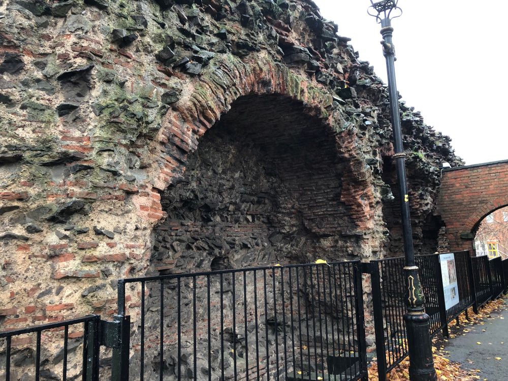 Photo of an ancient Roman brick wall about 8 foot high with big arches. 