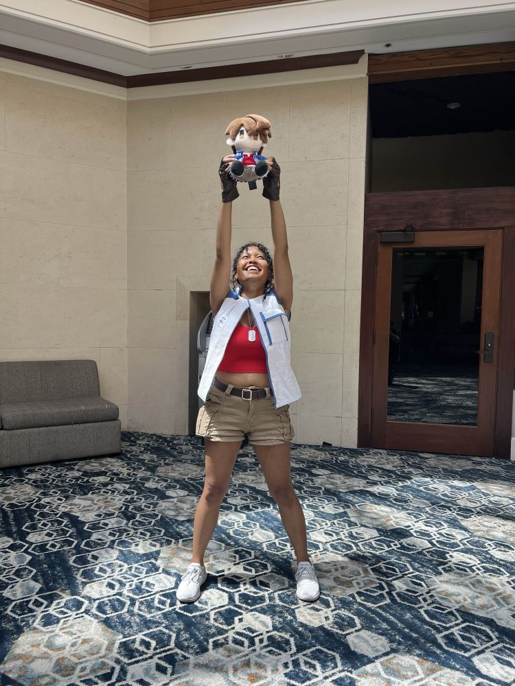A Lloyd Bannings cosplayer holding up a Lloyd plush like it’s Simba.