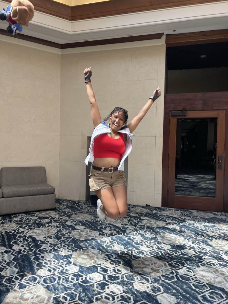 A Lloyd cosplayer jumping while a Lloyd plush goes flying in the corner.