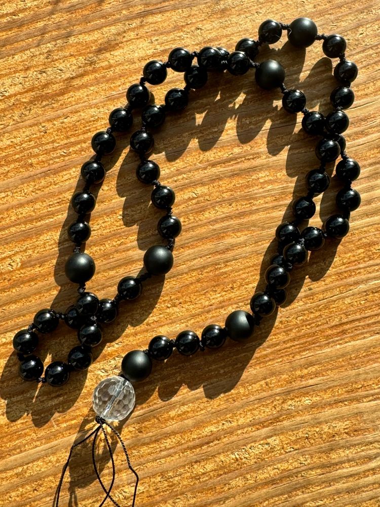 Black onyx rosary with a faceted clear quartz where the crucifix would traditionally go.