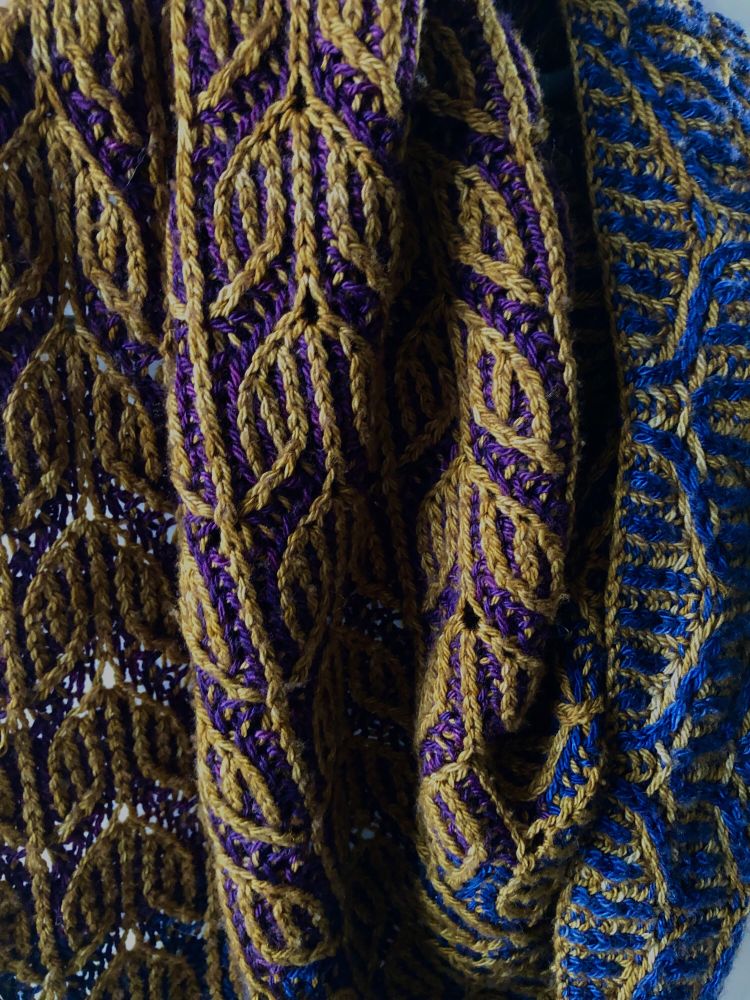a close up of the reversible brioche design, main colour gold, contrast colours plum and navy