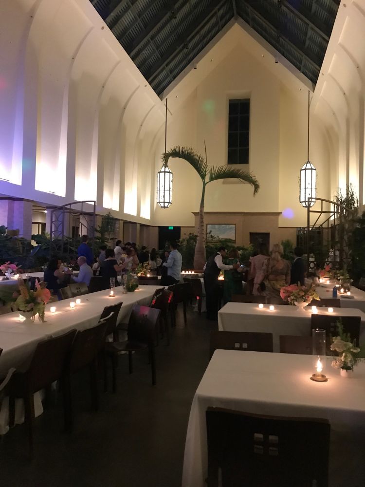 Interior of a vaulted space with banquet tables and people in the distance. 