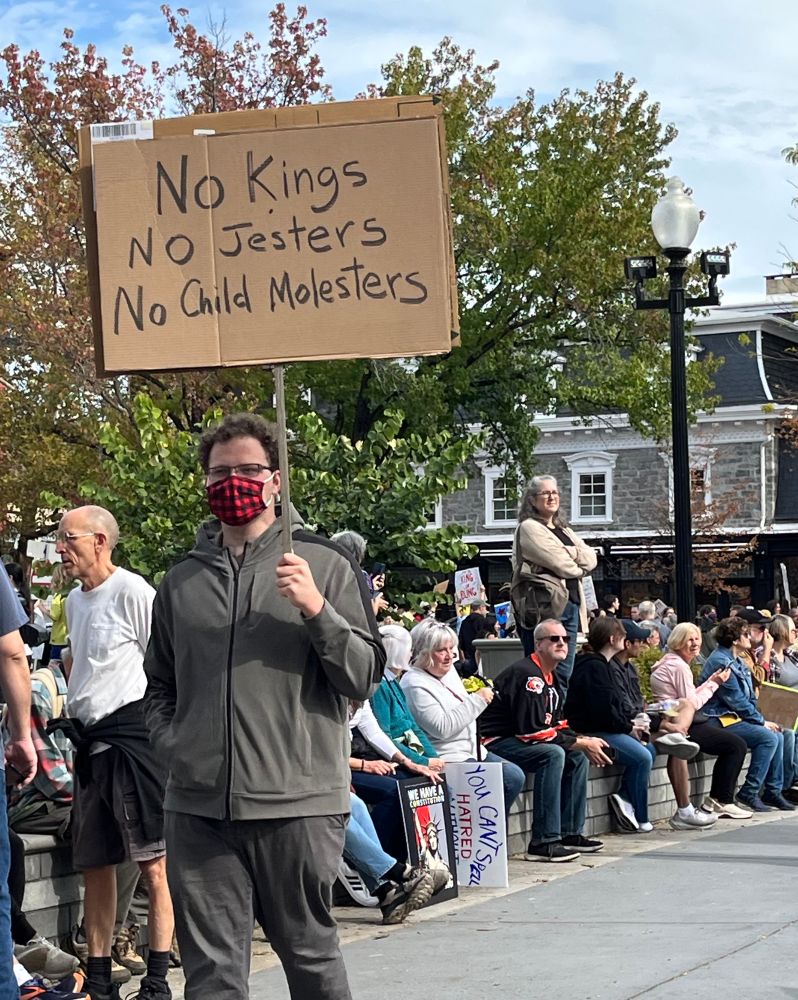 Patriotic protester with sign, “No Kings, no jesters, no child molesters”