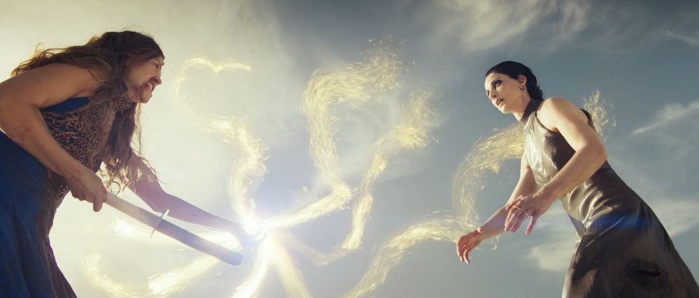 A low-angle shot of Moiraine (Rosamund Pike) and Lanfear (Natasha O'Keeffe) in third season finale of The Wheel of Time. Moiraine is removing Lan's Malkieri sword from her abdomen, and channeling with the Sakarnen in the process. 
