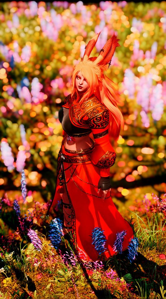 Ayashi in her WoL orange-red gear standing among a field of flowers, her face turned up towards the camera