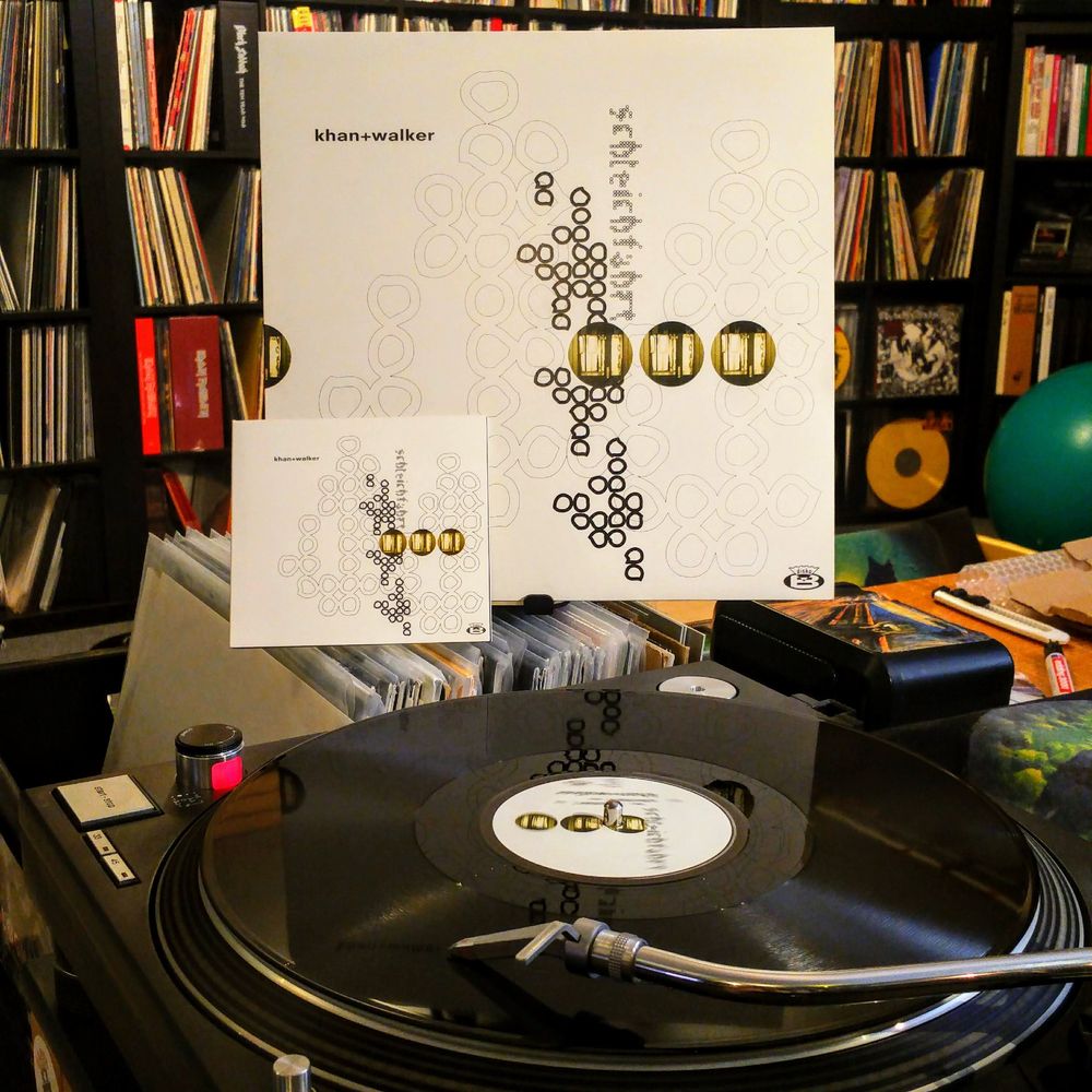 vinyl record "khan & walker - schleichfahrt / 1996 disko b db37" playing on the technics, lp cover and cd digipak beside it. record collection wall in the background.

