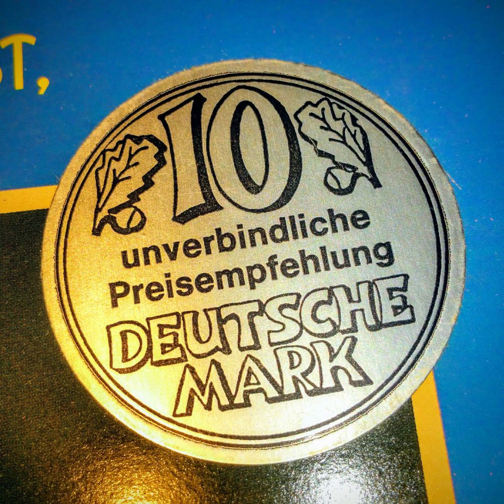 small round silver sticker on the front cover "10 Deutsche Mark unverbindliche Preisempfehlung" looking like a 1-DM coin