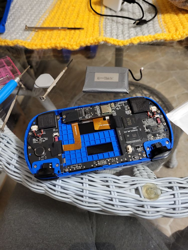 Anbernic 40xxH with backplate removed on a transparent glass table