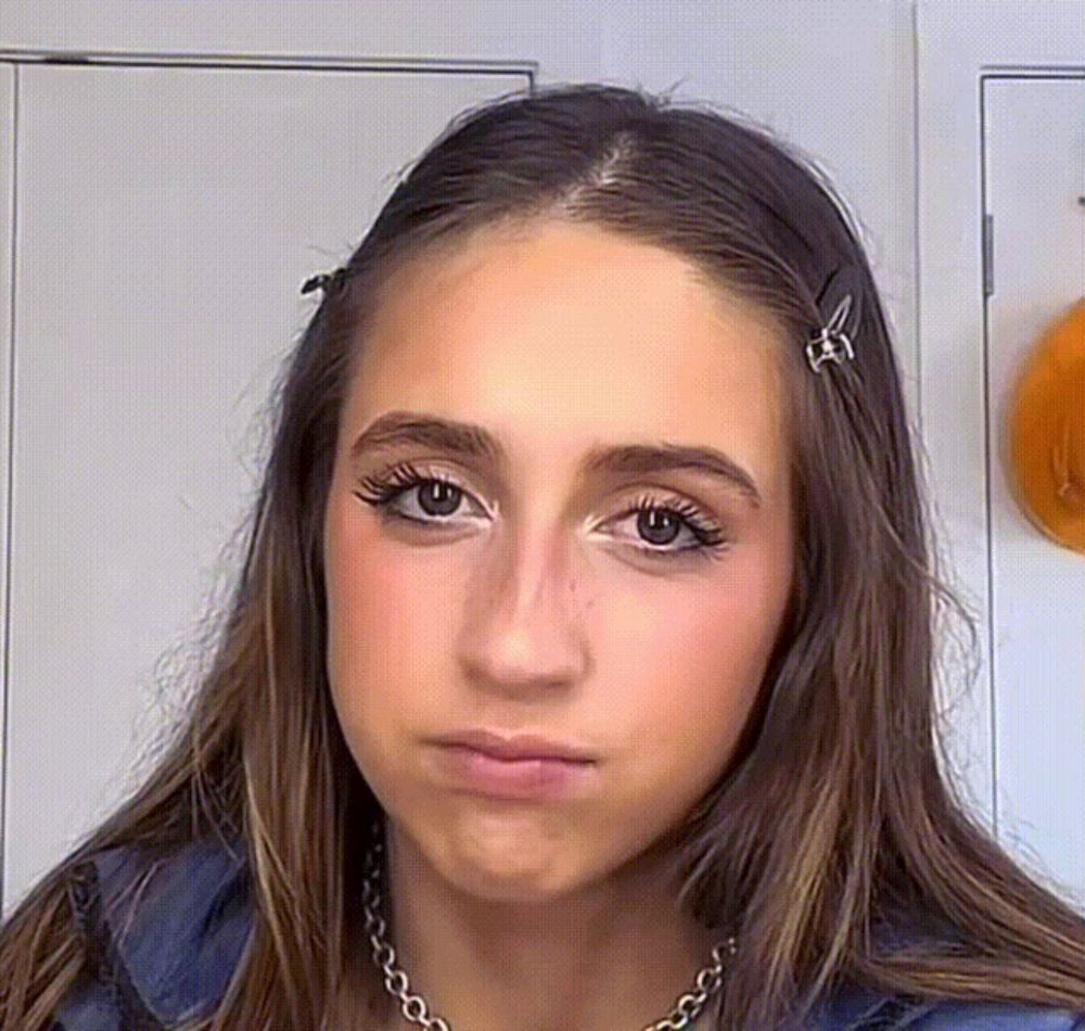 a close up of a woman 's face with a necklace and hair clips