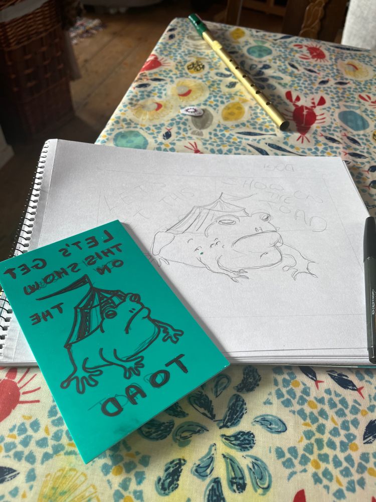 A pencil sketch, and a linoleum block marked with sharpie, of a toad with a circus tent on its back and the phrase “let’s get this show on the toad”