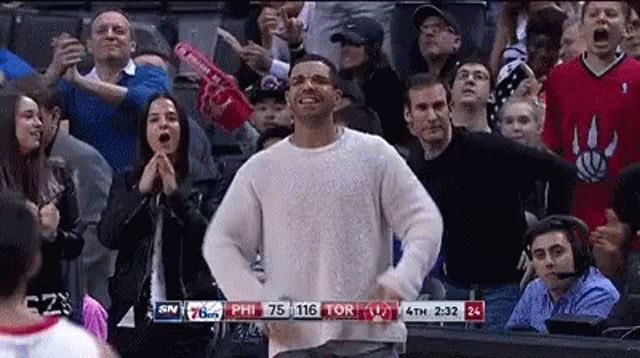 a man in a white sweater is dancing in front of a crowd of people .