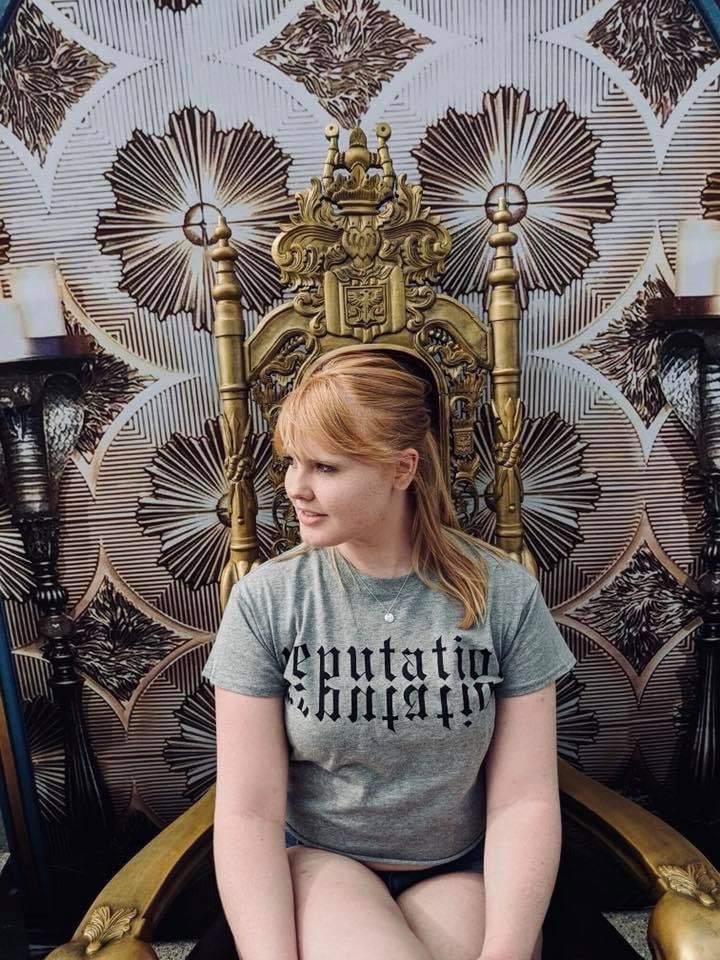 Seri with a reputation grey shirt sitting on the gold rep throne 