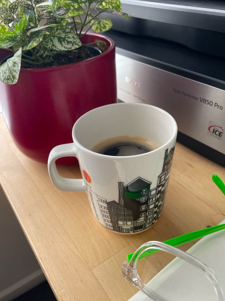 Coffee cup with black coffee on a desk with pot plant and glasses