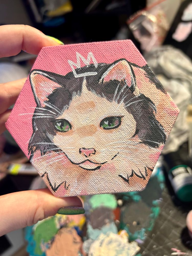 A person holding a painting of a white and gray cat. 