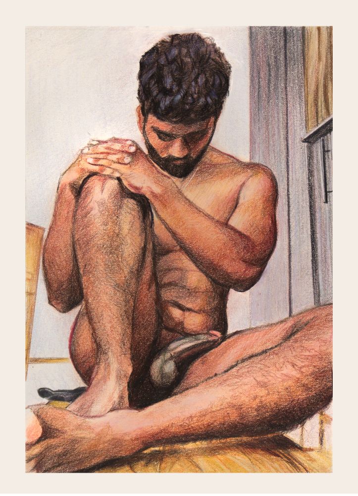 Head bent, hands on upraised knee, looking pensive. He sits on a laminate floor.