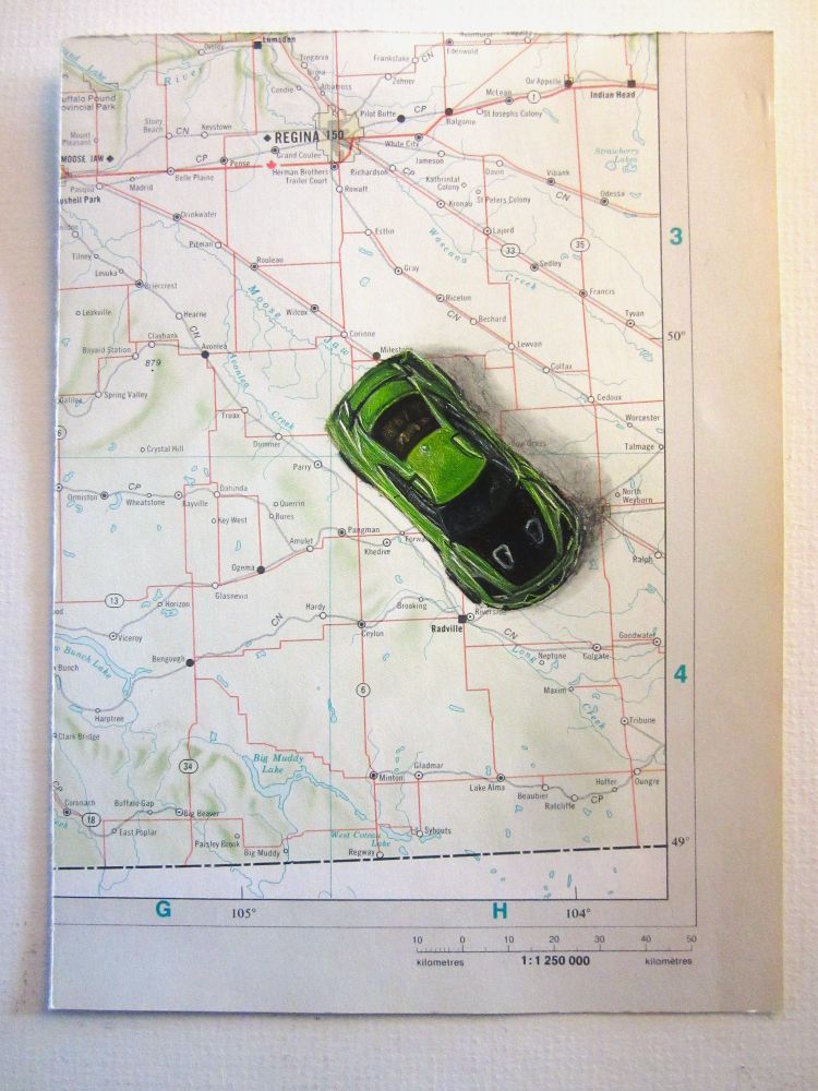  "Die (cast)", oil on map, 5 1/4 x 7", 2025 - $60(Cdn). A piece of a map showing Regina, Saskatchewan with a painting of a green & black Nissan GT Hot Wheels car on it.