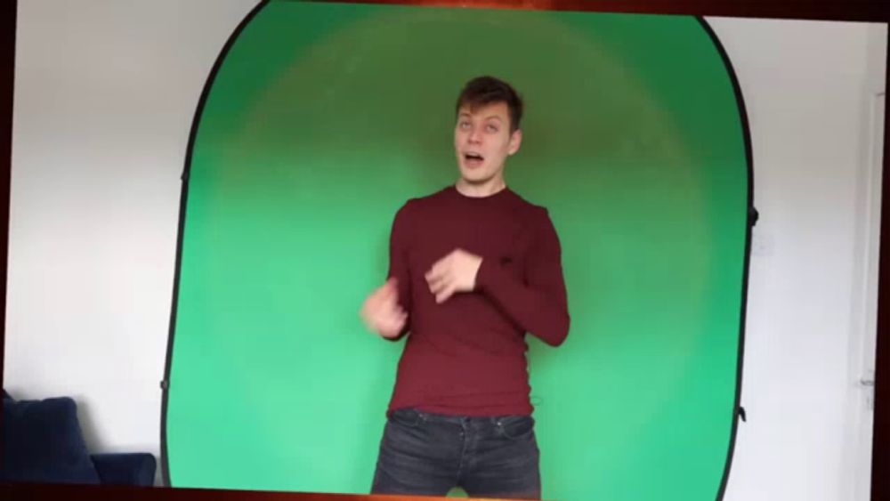 a man in a red shirt stands in front of a green background