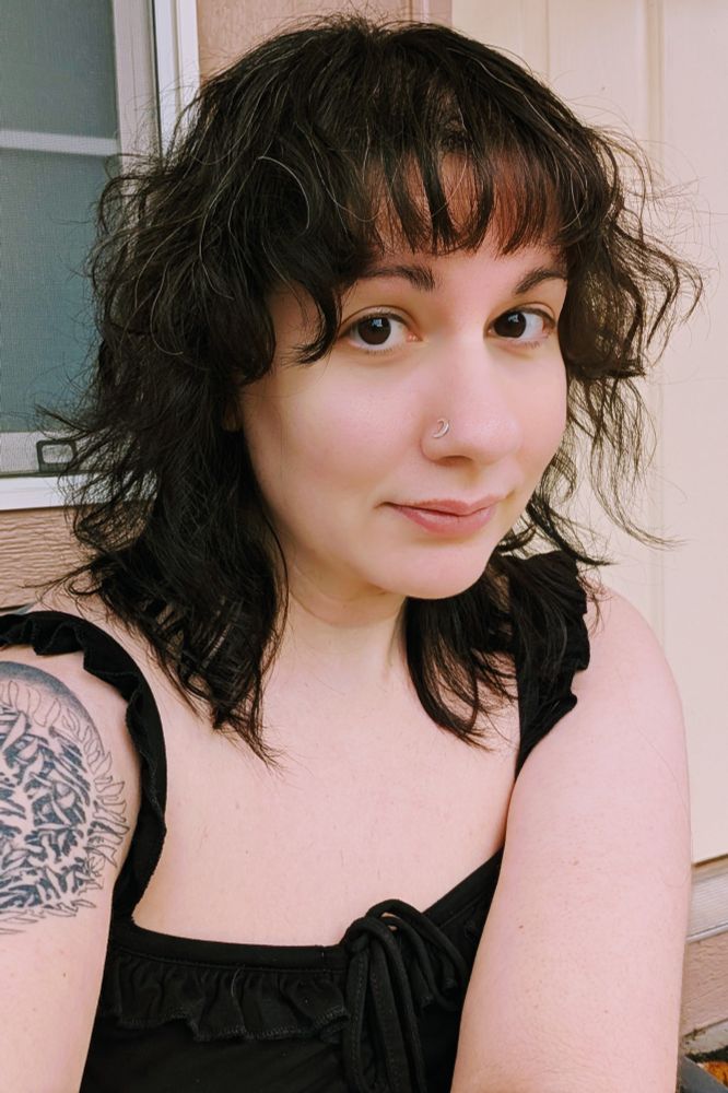 Luna looking at the camera from closer to a 3/4 angle with what appears to be a perfectly normal shoulder length curly haircut and bangs.