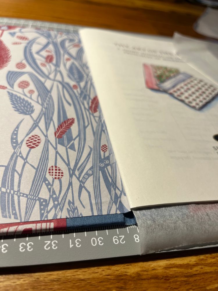 Book lying open, with decorative endpaper showing. 