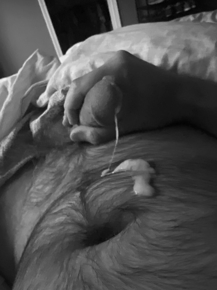 Black and white photo of hairy cock with cum dripping out on hairy belly